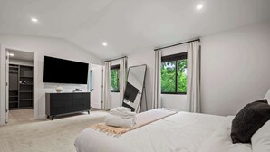 A bedroom with a bed, a TV, a wardrobe, and a mirror. - Newly Renovated 5BR/2.5BA w/ Jacuzzi! (Rochester Hills)