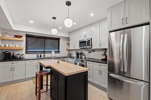 Una cocina moderna con una isla central, electrodomésticos de acero inoxidable y detalles de madera.