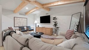 A modern living room with a sofa, chairs, a coffee table, a TV, and a cabinet. - Newly Renovated 5BR/2.5BA w/ Jacuzzi! (Rochester Hills)