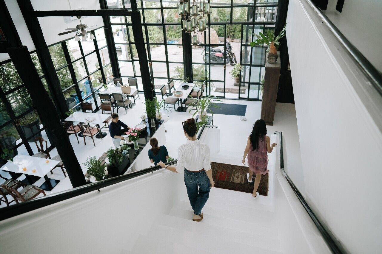 Un amplio espacio interior con techo alto, ventanas grandes y una escalera que conduce a un nivel superior.
