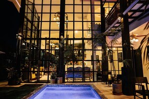 A pool area with a glass enclosure, potted plants, and a seating area visible through the glass.