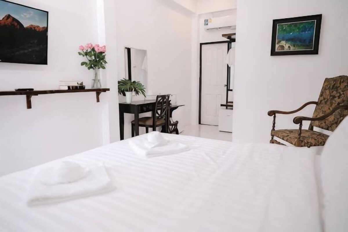 A hotel room with a bed, a desk, a chair, a mirror, and a picture on the wall.