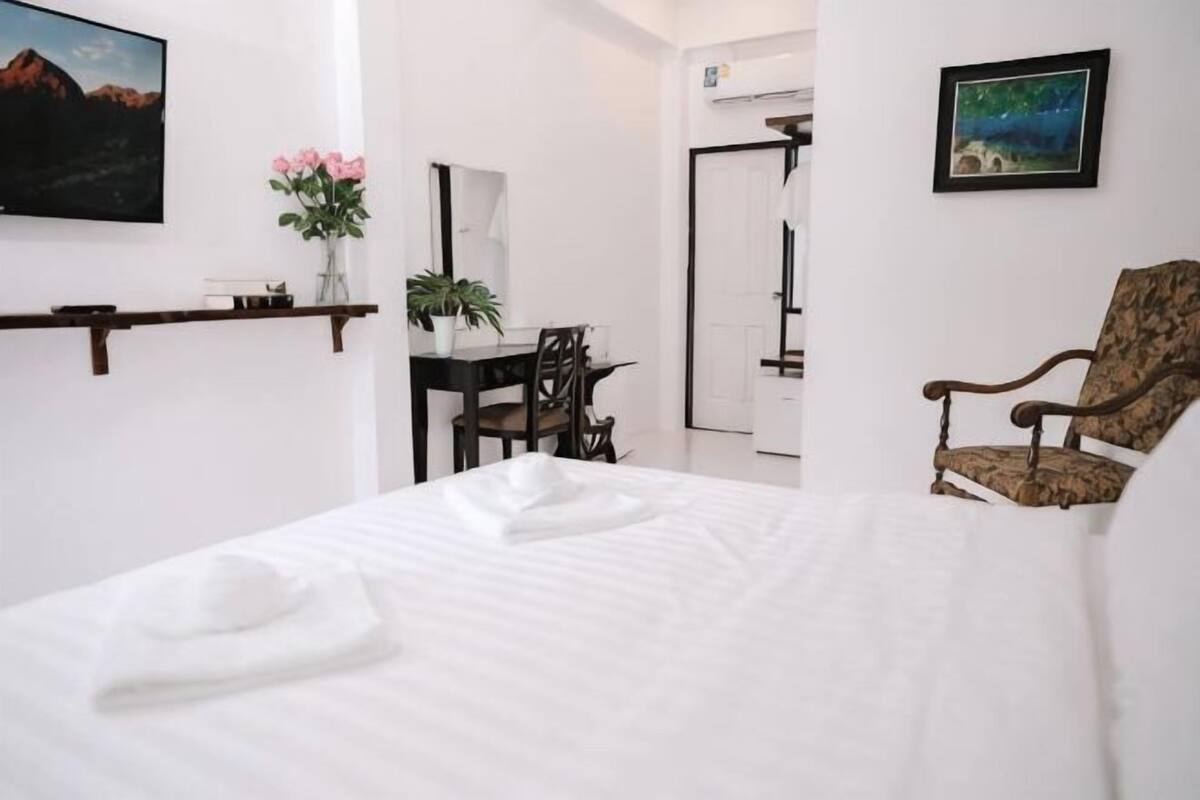 A hotel room with a bed, a desk, a chair, a mirror, and a picture on the wall.