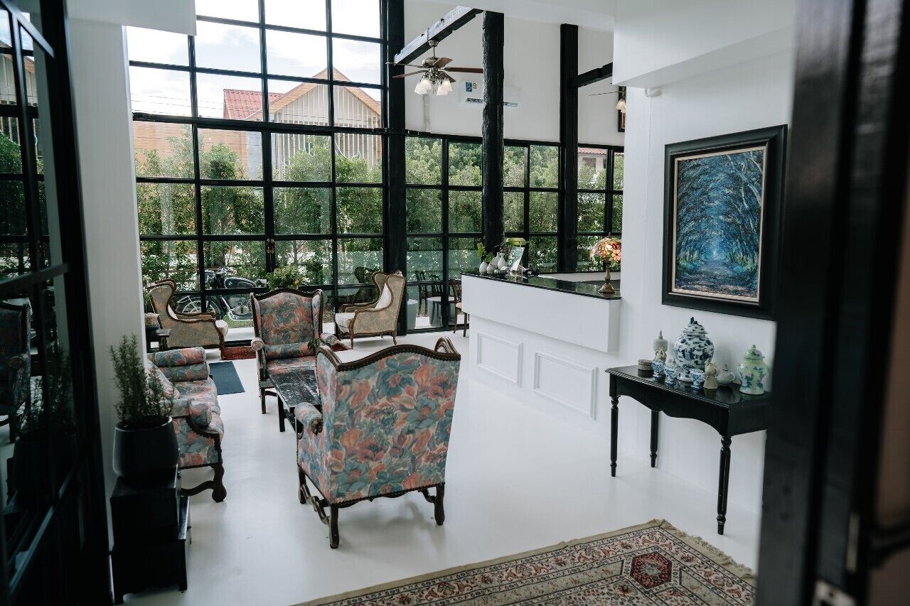A spacious room with large windows, a black ceiling fan, and a framed painting on the wall.