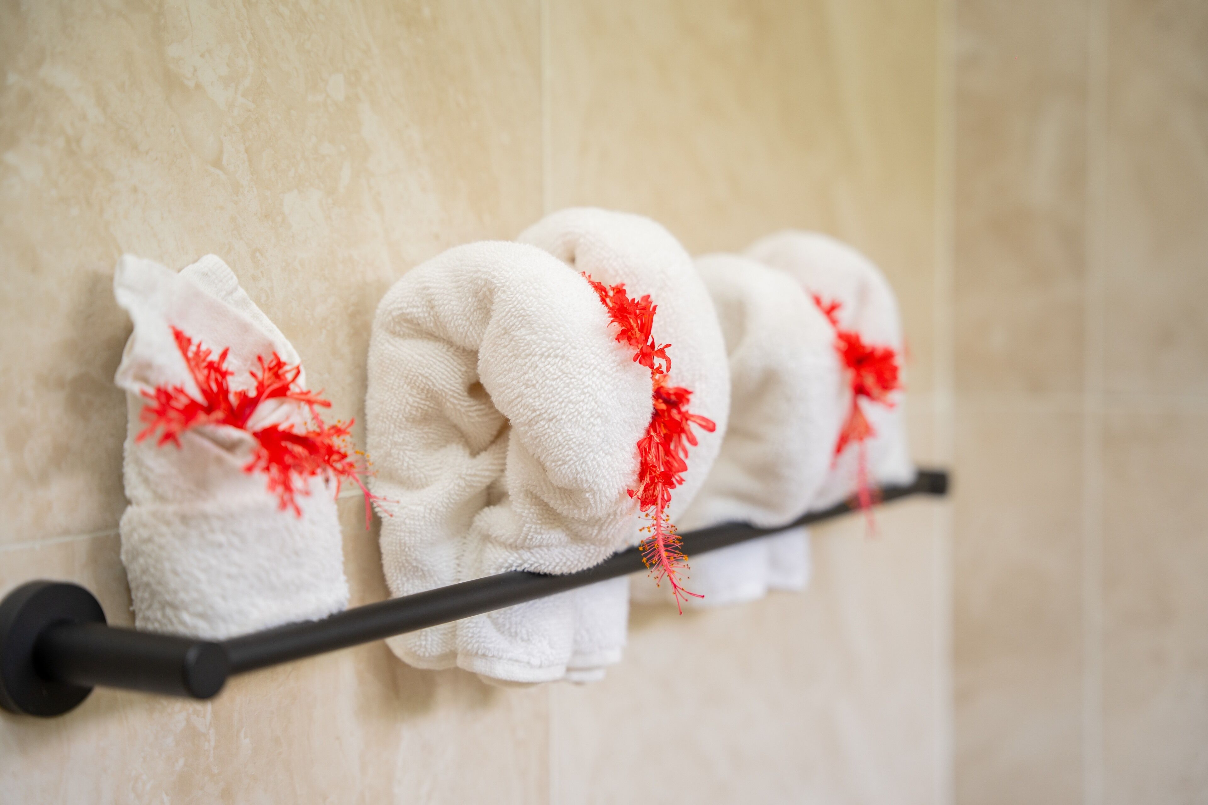 A towel rack with neatly folded towels, each adorned with a red floral decoration.