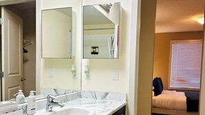 Un baño con lavamanos doble, un espejo grande y un vestidor.