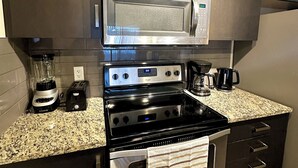Una cocina moderna con electrodomésticos de acero inoxidable, encimera de granito y armarios oscuros.