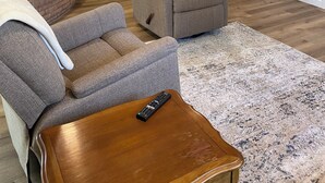 Una sala de estar con chimenea, un sofá, una mesa de centro y un televisor montado en la pared.