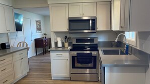 Una cocina moderna con armarios blancos, electrodomésticos de acero inoxidable y una mesa de comedor de madera.
