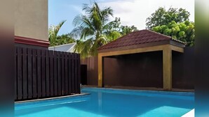 A swimming pool with a wooden deck and a covered area.