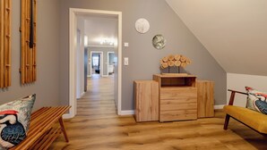 A modern interior with a wooden bench, a wooden dresser, and a bench with a colorful cushion. - Hünzinger Dorfschmiede - Holiday apartment Specht (Walsrode)