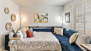 Une chambre à coucher moderne avec un grand lit, un canapé bleu et un tableau coloré accroché au mur.