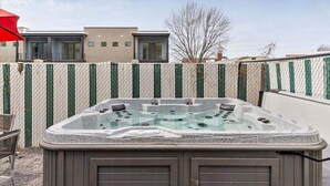 Un jacuzzi dans un jardin, avec une maison moderne en arrière-plan.