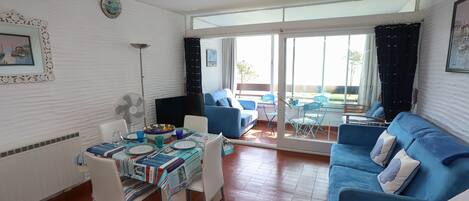 A dining area with a table set for four, a blue sofa, and a large window with a view of the outdoors.