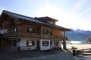 A wooden chalet with balconies, a wooden deck, and a view of snow-capped mountains.