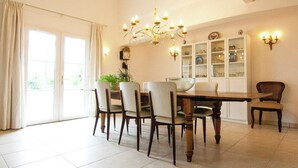 Un comedor con candelabro, mesa, sillas y una vitrina con puertas de vidrio.