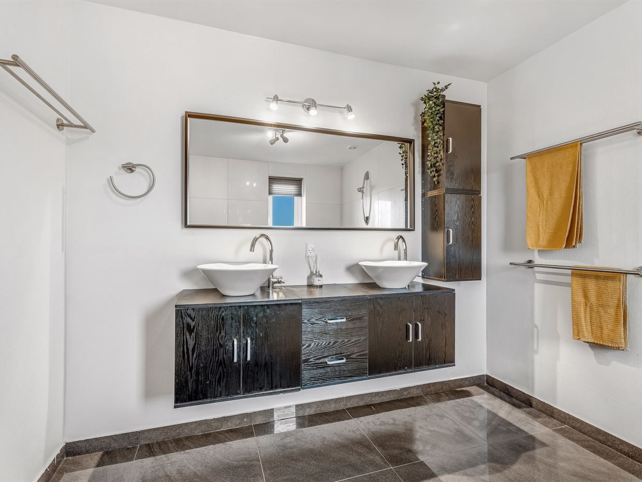 Une salle de bain moderne avec deux lavabos, un grand miroir et un meuble en bois.