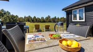 An outdoor seating area with wicker furniture, a table with magazines, a pitcher, and a basket of lemons. - "Danika" - 1.5km from the sea by Interhome (Væggerløse)