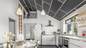 A modern kitchen with white cabinetry, a central island, pendant lighting, and a view of the adjacent bathroom. - "Danika" - 1.5km from the sea by Interhome (Væggerløse)