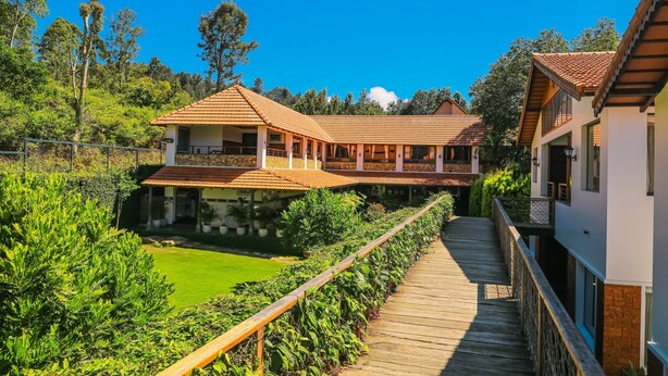 A large house with a wooden deck and a swimming pool. - The Story Resorts & Spa (Yercaud)