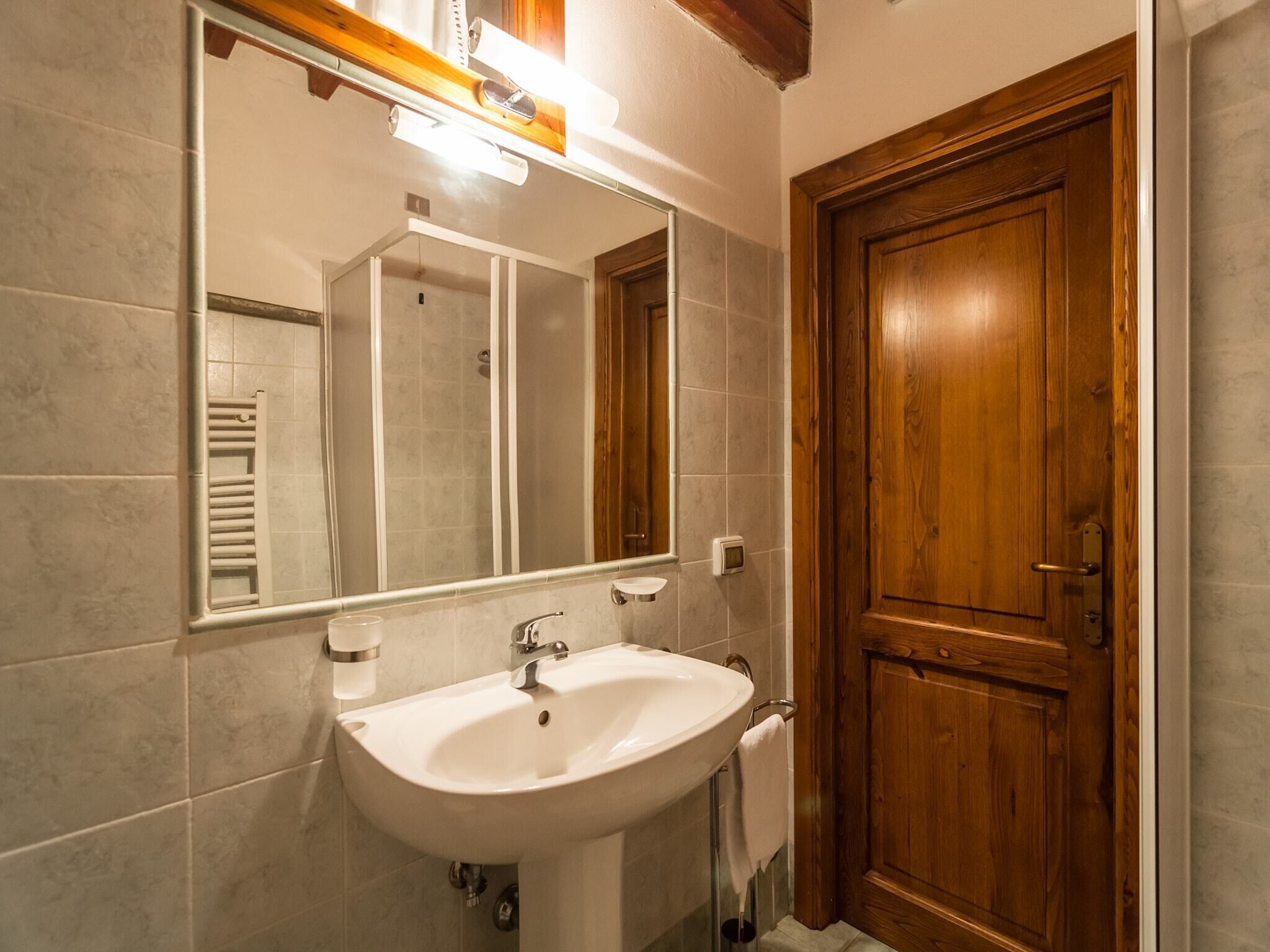 Un baño con un lavamanos blanco, una puerta de madera y un espejo.