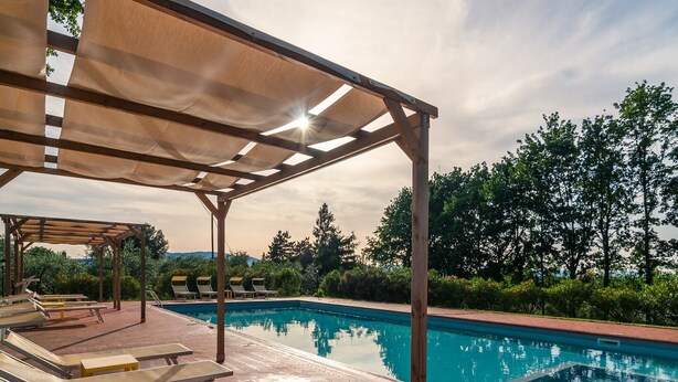 Ein Poolbereich mit Liegestühlen und einer Pergola.