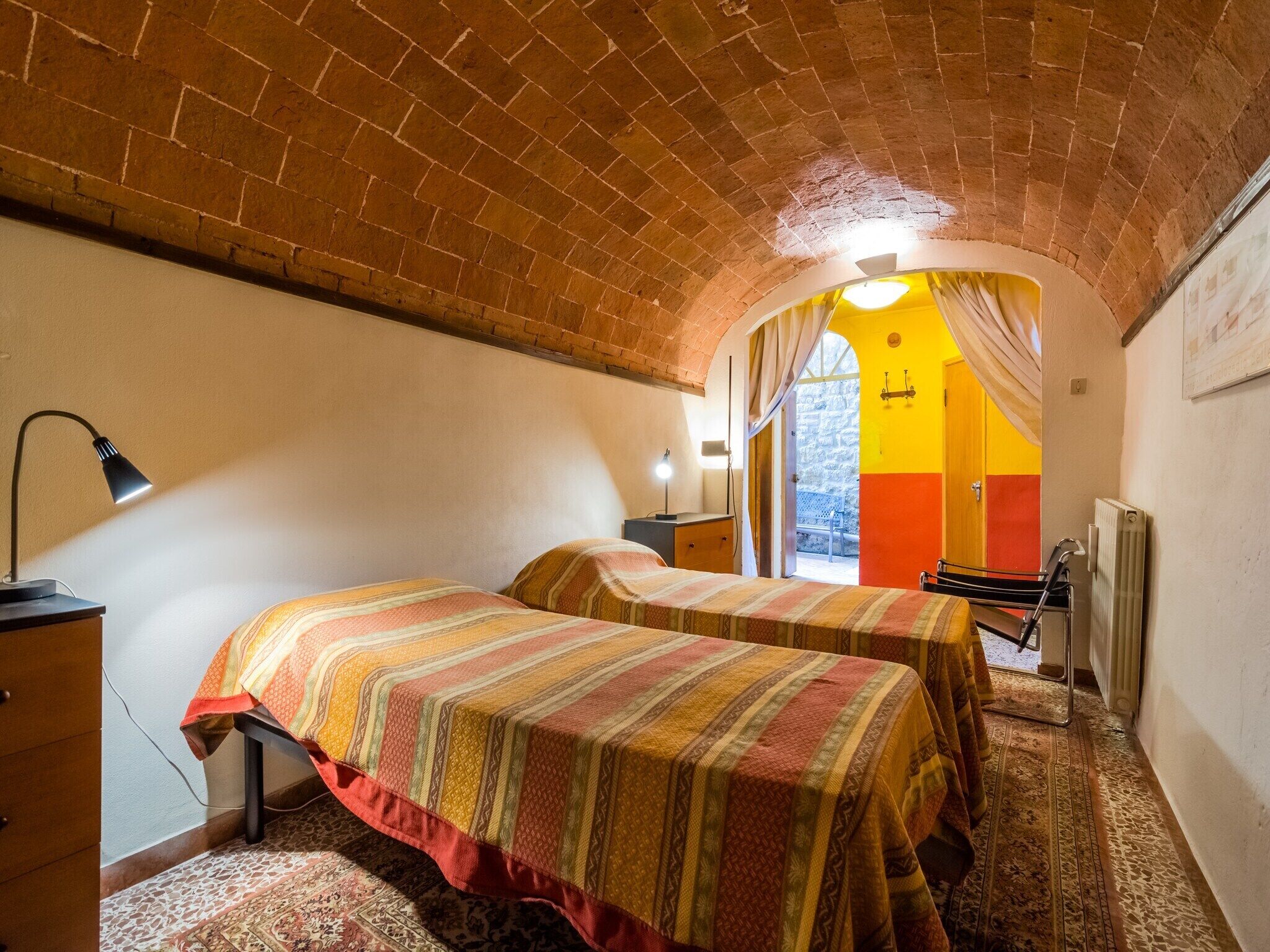 A room with two beds, a desk, a lamp, and a radiator.