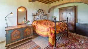 A bedroom with a wooden ceiling, a metal bed frame, a wooden dresser, a mirror, and a door.
