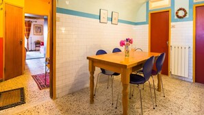 A dining area with a wooden table and blue chairs, a bottle of wine, and a glass on the table.