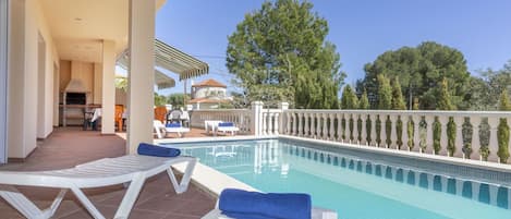A poolside area with lounge chairs and a barbecue.