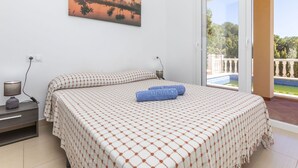 A bedroom with a bed, a nightstand, a lamp, and a painting of a sunset.