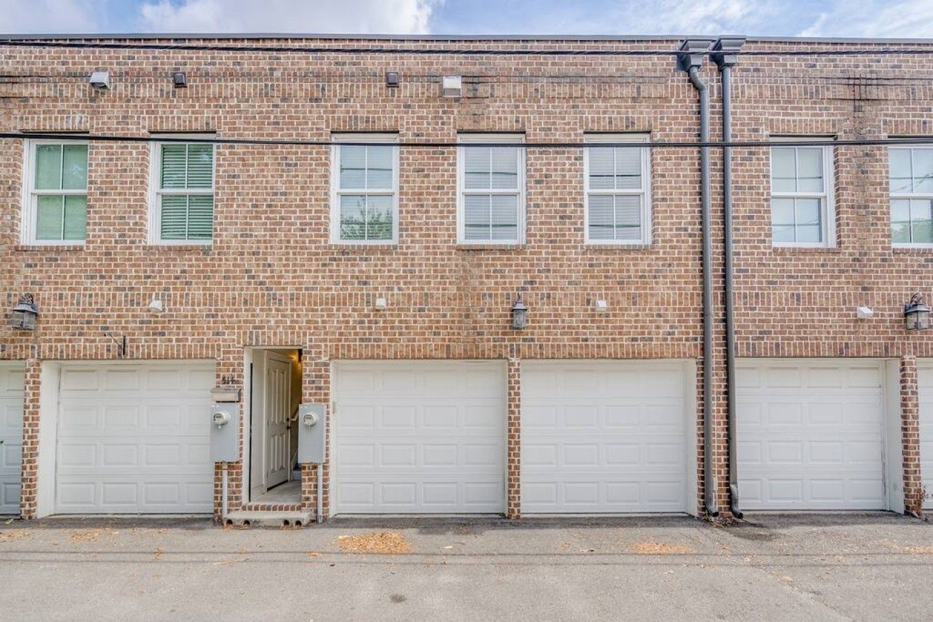 Un bâtiment en briques avec trois portes de garage et une petite porte d’entrée.