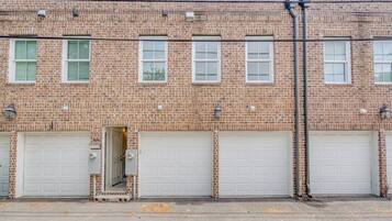 Un bâtiment en briques avec trois portes de garage et une petite porte d’entrée.
