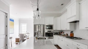 A modern kitchen with white cabinetry, stainless steel appliances, and a marble island. - Liberty House - 3 Bedroom Downtown with Easy Parking (Savannah)