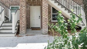 A two-story brick building with a central balcony, white railings, and a staircase leading to the entrance. - Liberty House - 3 Bedroom Downtown with Easy Parking (Savannah)