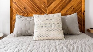 A bed with a wooden headboard, two pillows, and a white bedspread. - Garden Home at Liberty Estate (Savannah)