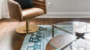 A room with a brown leather chair, a glass coffee table, and a guitar on the wall. - Garden Home at Liberty Estate (Savannah)