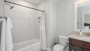 Een badkamer met douche, toilet en wastafel.