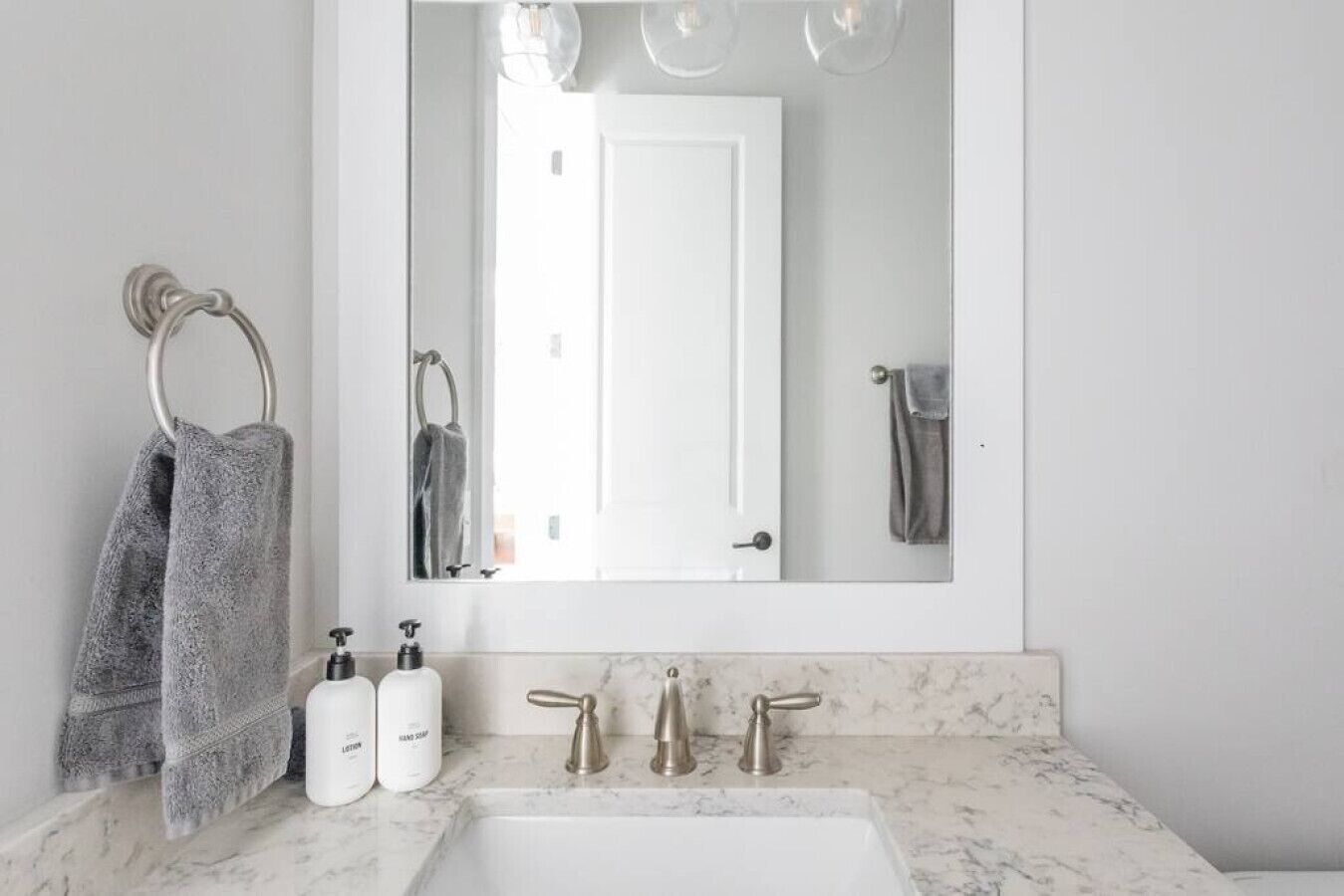 A bathroom with a white sink, two hand soap bottles, and a mirror above the sink.