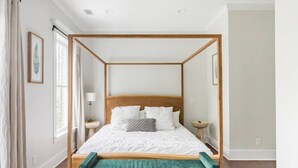 A four-poster bed with white linens, a wooden headboard, and a green bench at the foot of the bed. - Radiant Estate in the Heart of Savannah (Savannah)