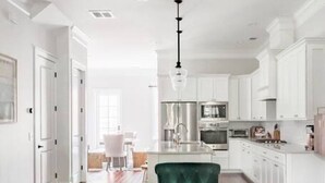A modern kitchen with white cabinets, a central island, and stainless steel appliances. - Radiant Estate in the Heart of Savannah (Savannah)