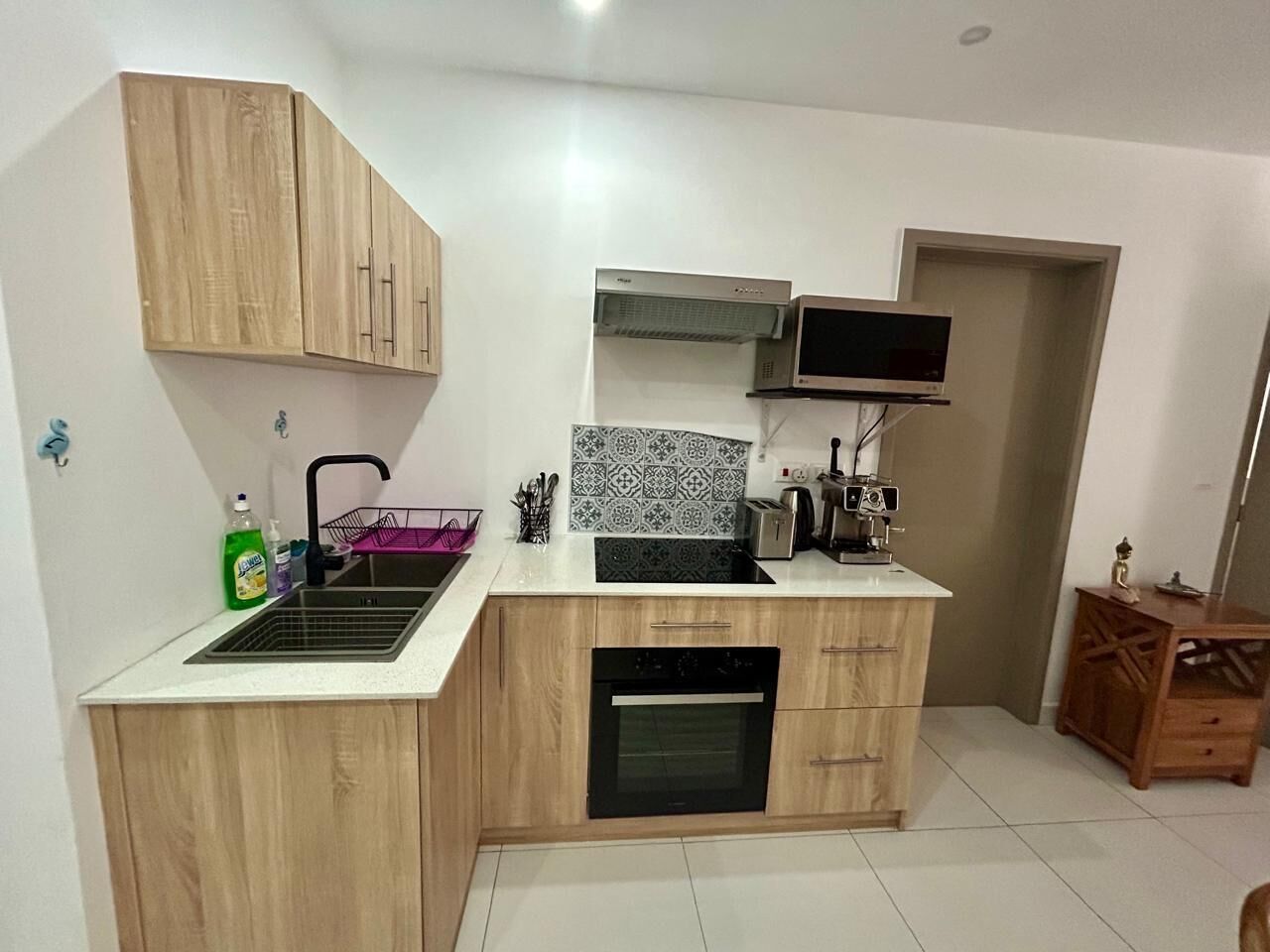 A compact kitchen with wooden cabinets, a built-in oven, a sink, and a microwave.