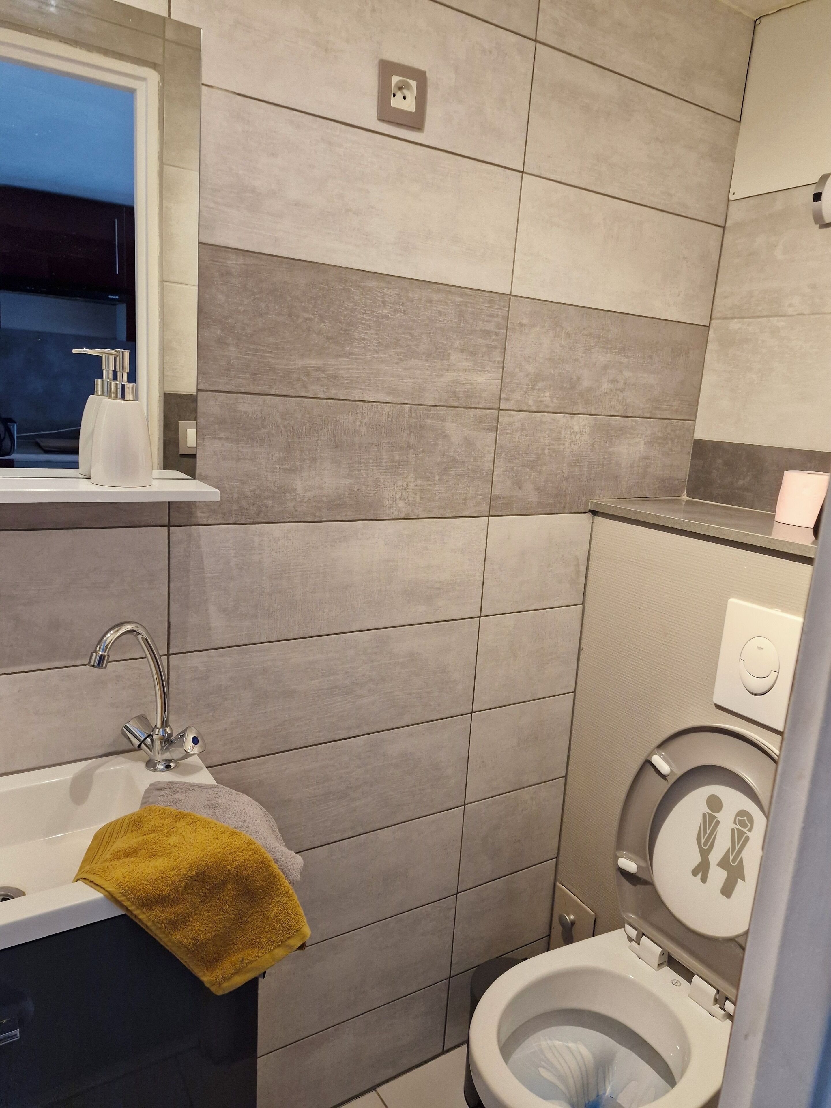 Een moderne badkamer met een wastafel, spiegel en toilet.