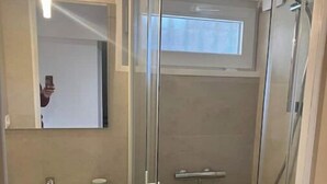 A modern bathroom with a glass-enclosed shower, a white sink, and a mirror above it. - Room in Angers near the streetcar with shared kitchen and bathroom (Angers)