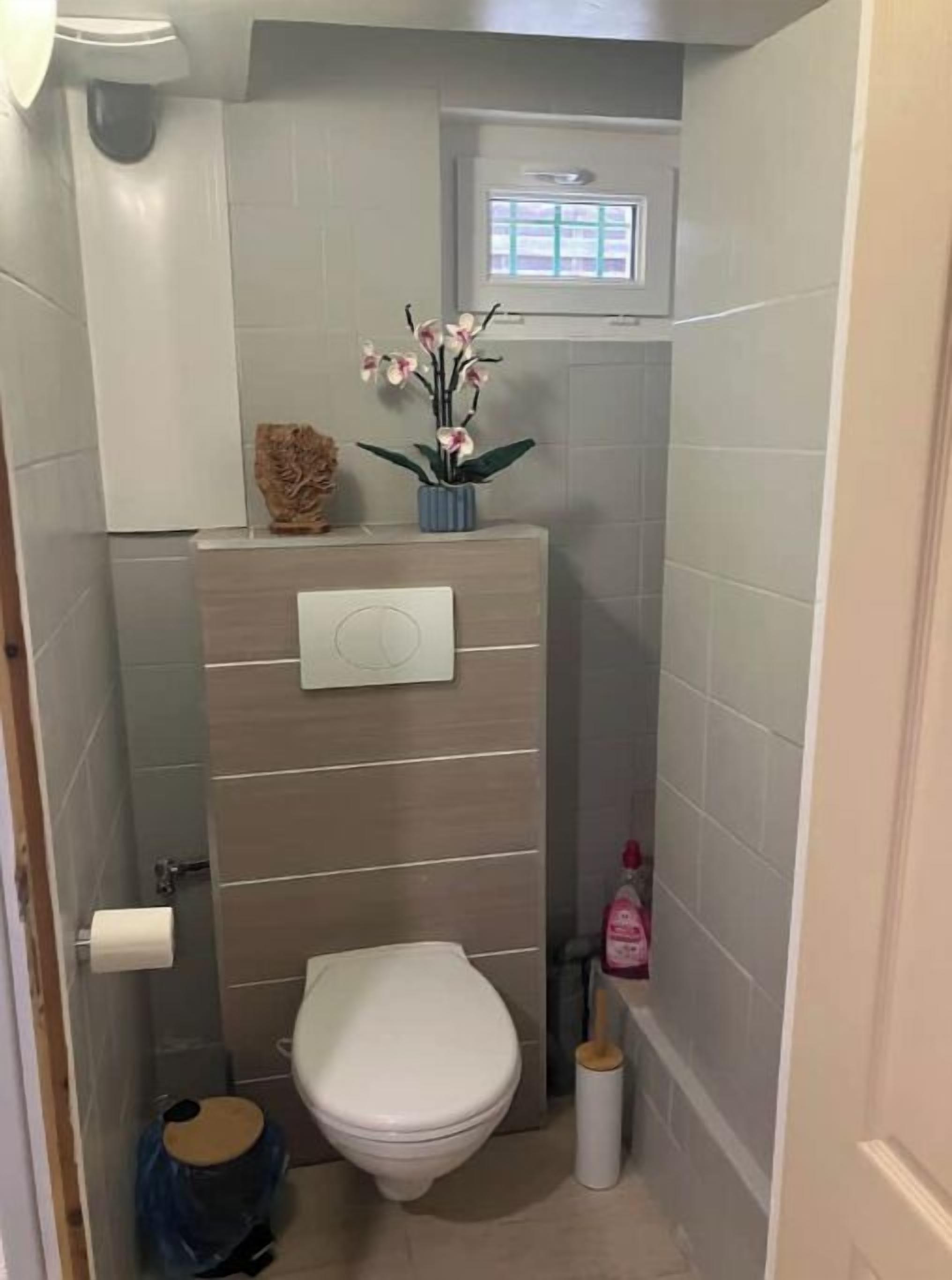 A small, compact bathroom with a toilet, a sink, and a window.
