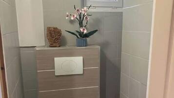 A small, compact bathroom with a toilet, a sink, and a window.