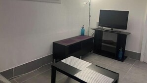A small, modern living room with a TV, a bench, and a floor lamp. - Room in Angers near the streetcar with shared kitchen and bathroom (Angers)