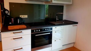 Une cuisine compacte équipée d’une cuisinière, d’un four, d’un évier et d’un four à micro-ondes placé au-dessus de la cuisinière.