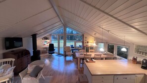 A spacious attic room with a large window, wooden furniture, and a television.