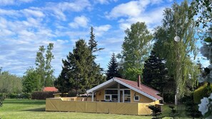 Una casa con techo inclinado, ventanas grandes y patio cercado.